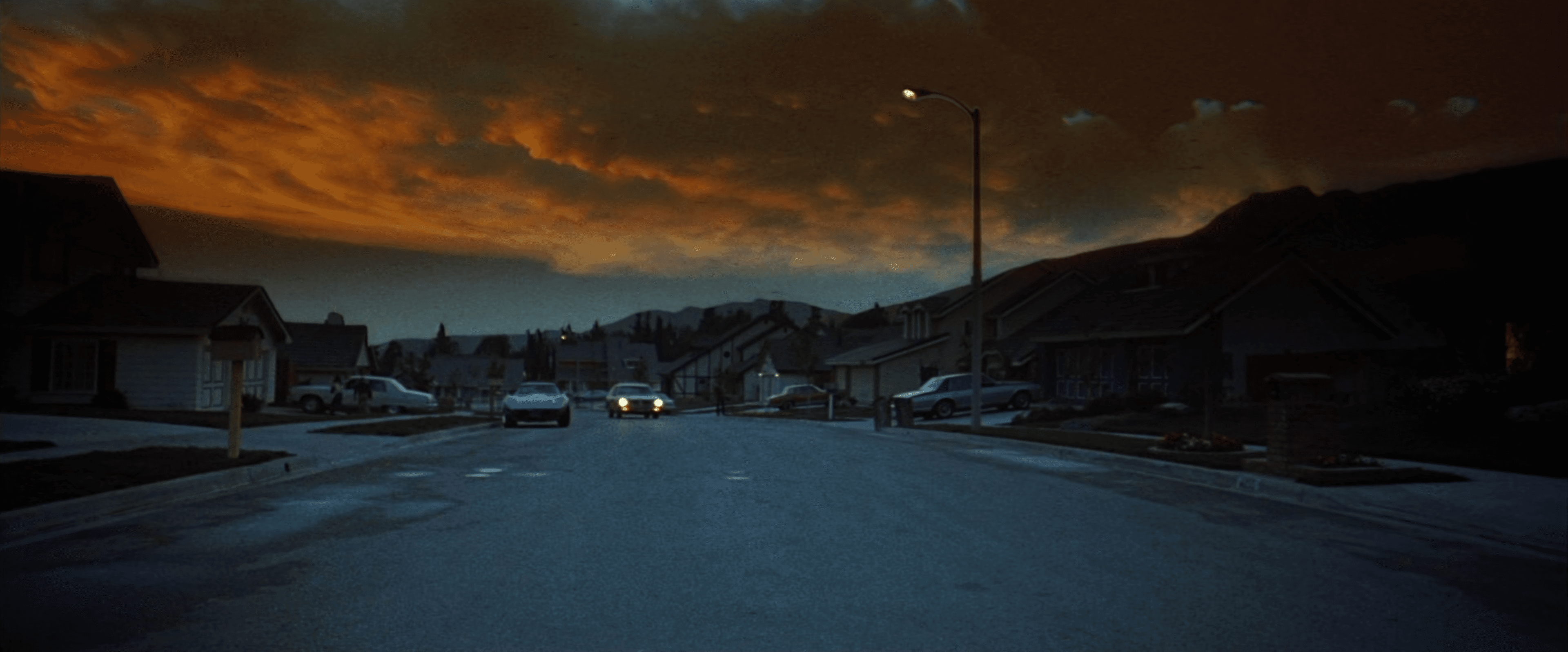 A suburban neighborhood street with ominous clouds overhead