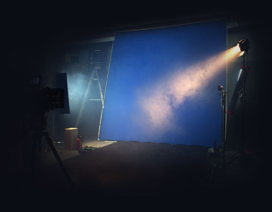 An illuminated blue screen in a dark fog filled studio