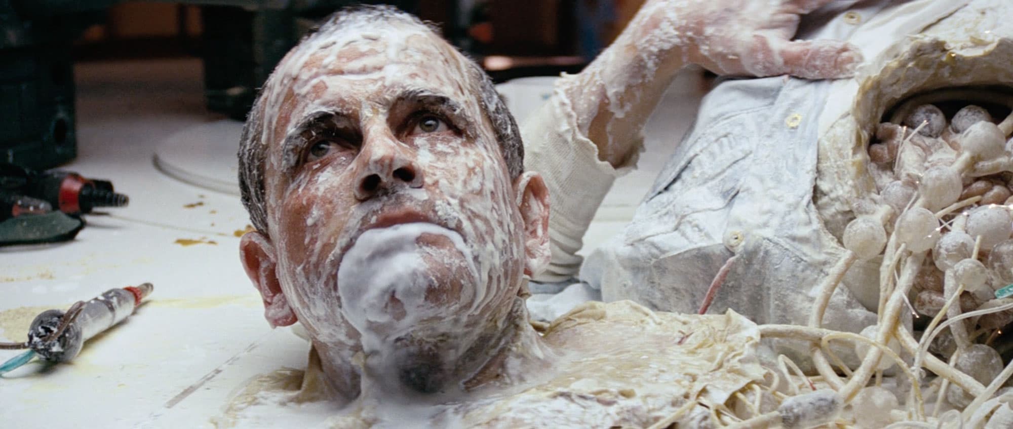 a still frame from Alien (1979) showing a cyborg covered in white fluid