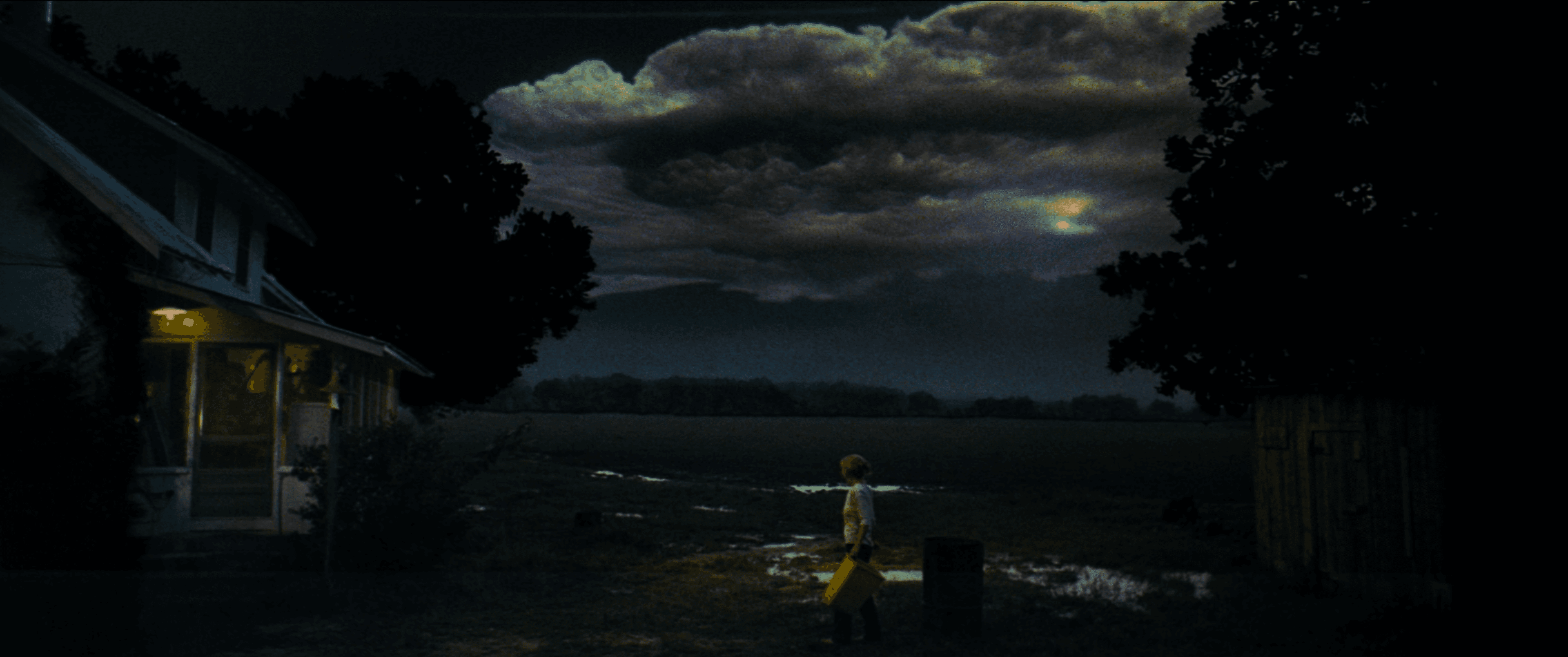 Still frame from "Close Encounters of the Third Kind" of a woman walking in the grass with ominous clouds overhead.