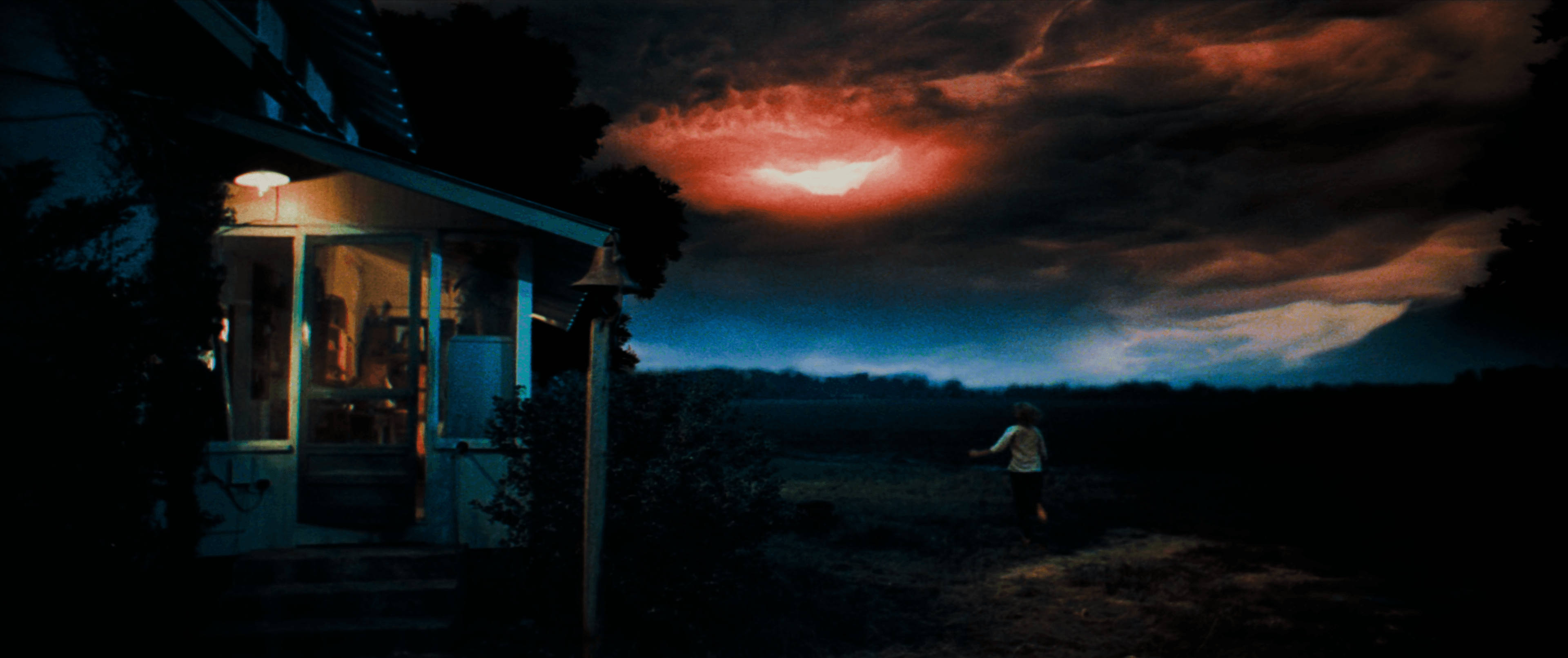 A still frame from the film "Close Encounters of the Third Kind" features a woman running in the grass with illuminated clouds overhead.