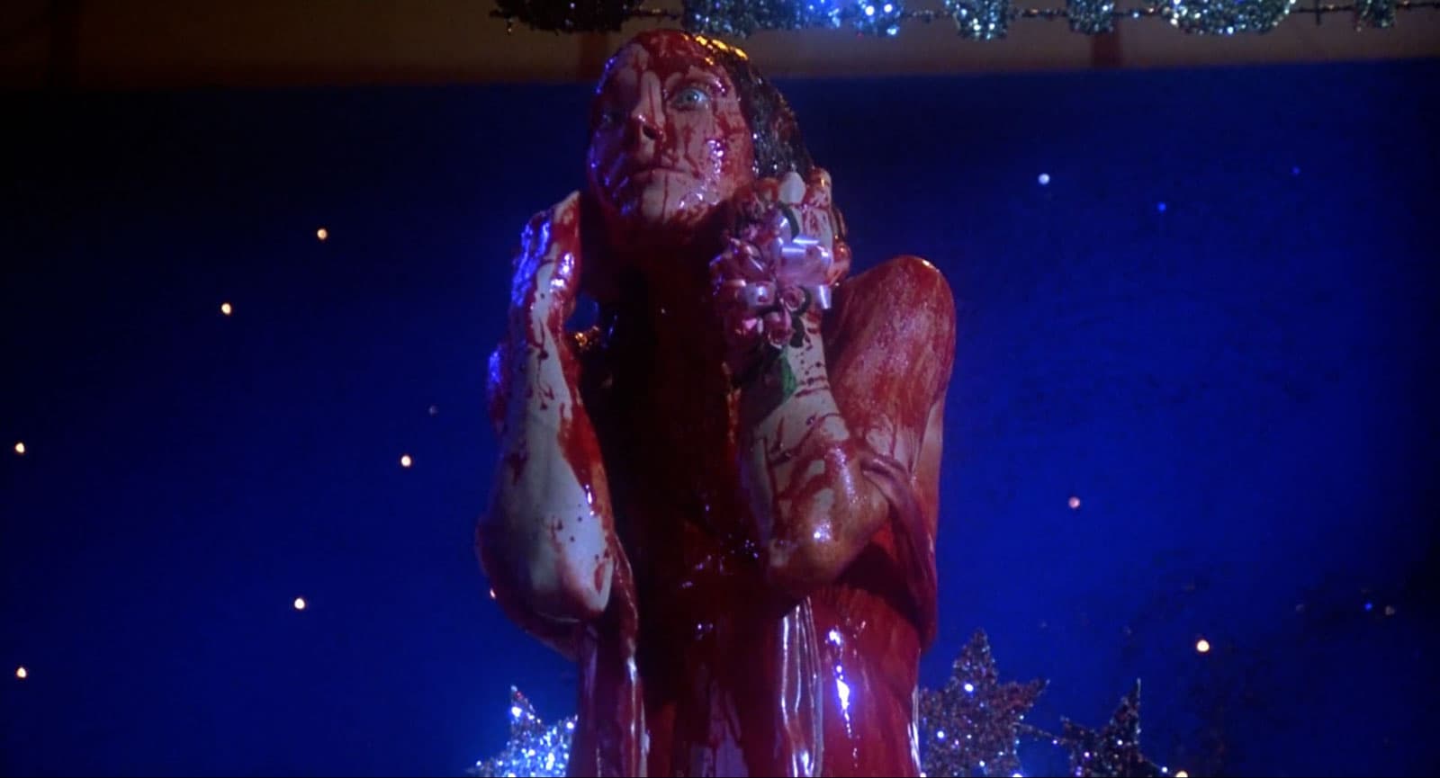 Carrie standing on stage drenched in blood
