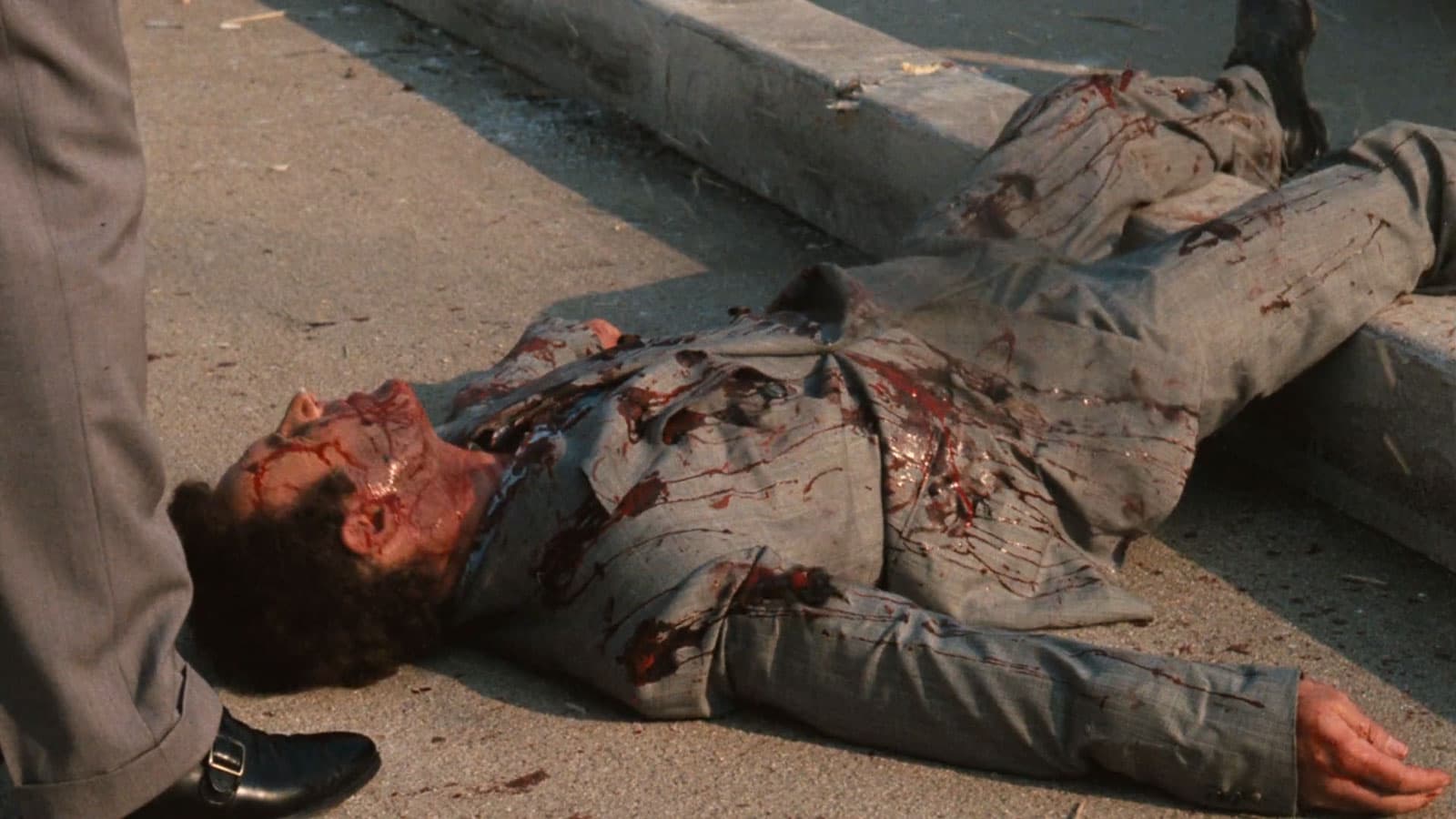 man laying on ground covered in bullet holes and fake blood